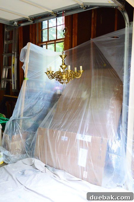 Chandelier carefully suspended in the garage painting station, secured with a bungee cord for even spray application.