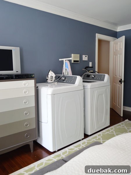 Starting Our Laundry Room Transformation 3 Temporary laundry setup in a bedroom during renovation, showing a washing machine positioned for use with essential items nearby, emphasizing functional living during home improvements.