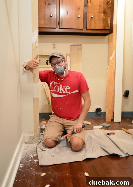 Starting Our Laundry Room Transformation 4 Demolition in progress in a home, showing a wall partially torn down with debris on the floor, indicating active renovation for a laundry room.