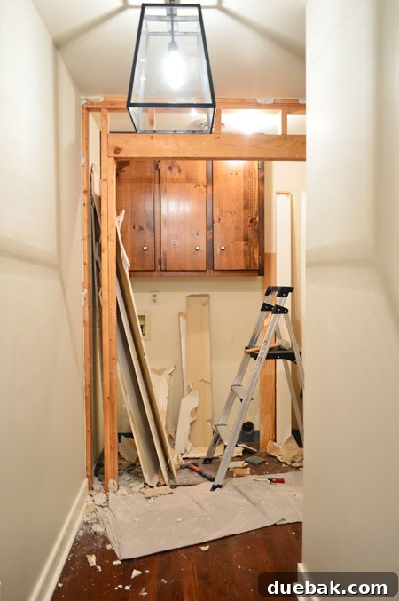 The Ultimate Laundry Room Makeover: From Demolition to Design 6 Drywall demolition in progress using a mallet and crowbar