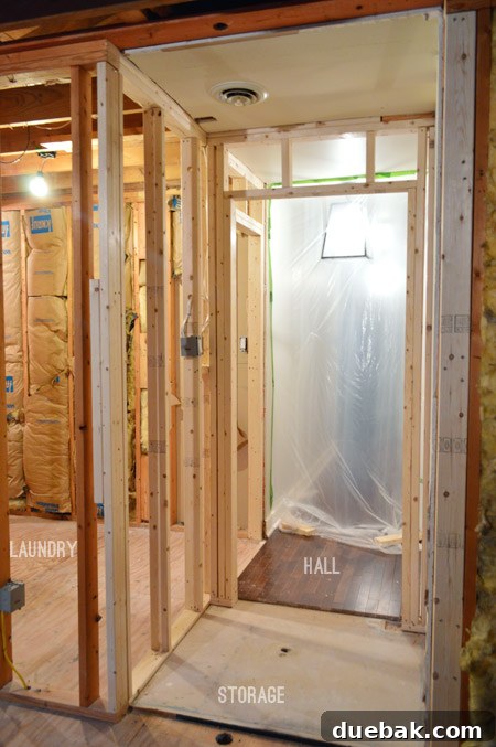 Routing New Laundry Exhaust Systems 3 Framing for a new room, viewed past a protective plastic sheet for attic heat management, showcasing construction progress