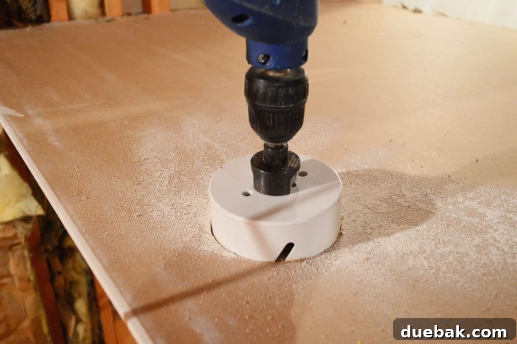 drill with hole cutting bit attached sawing through drywall sheet