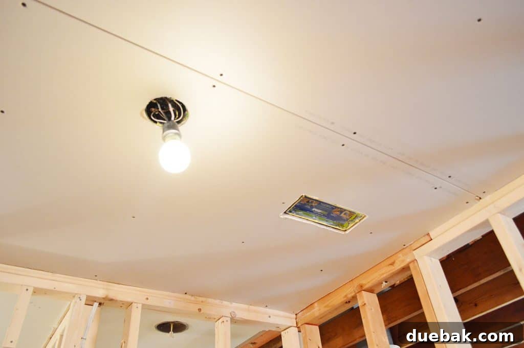 drywall hung in ceiling with hole cut for light and HVAC vent