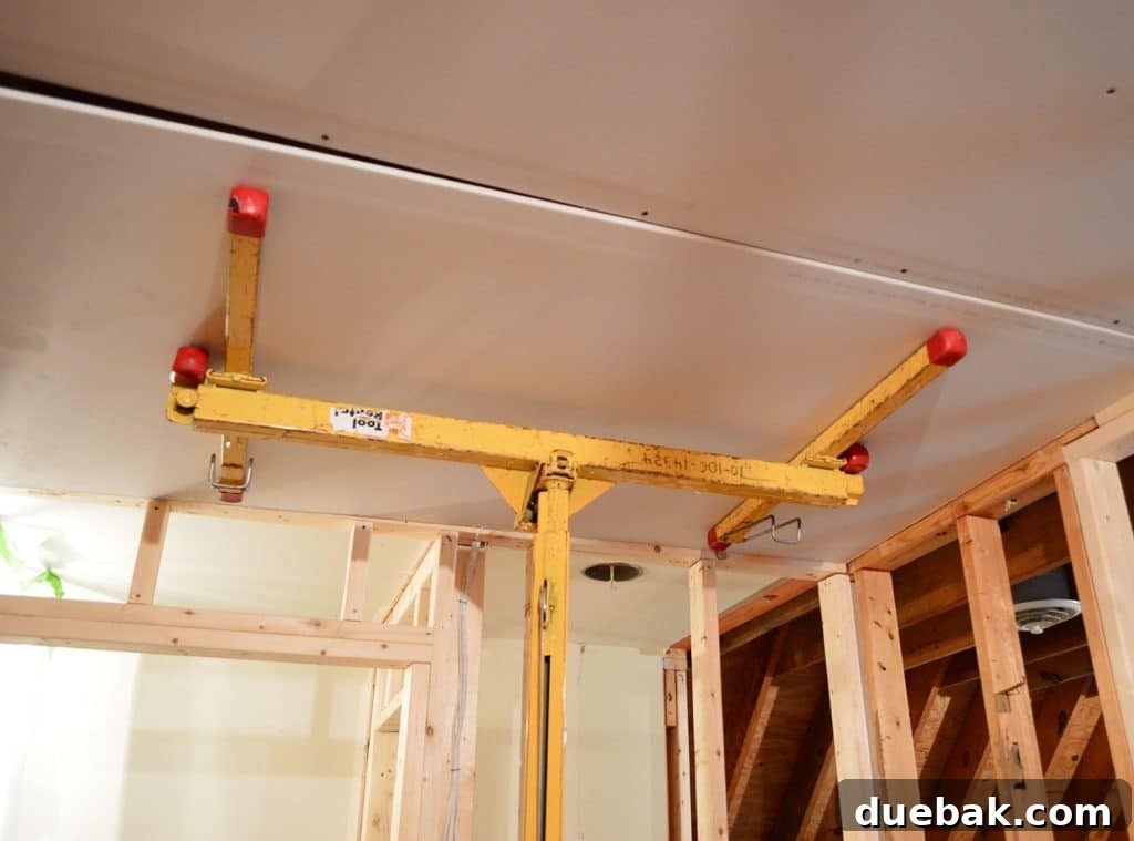sheetrock panel held against ceiling of laundry room using drywall lift