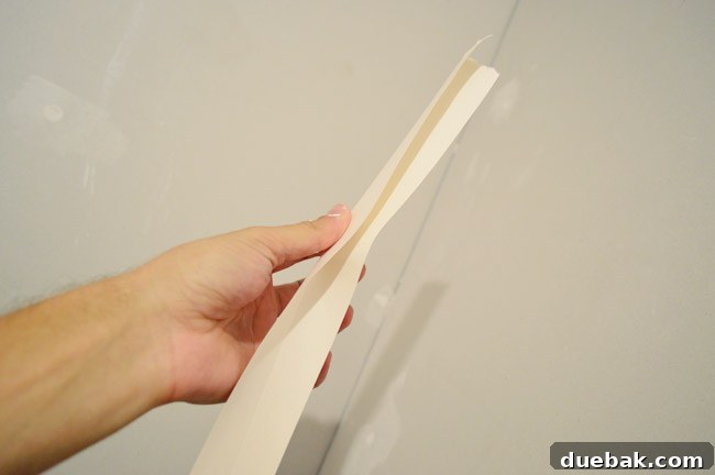 hand folding drywall tape along seam before pressing in corner 