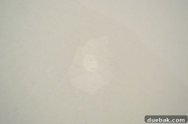 screw head with dried joint compound over it that has shrunk slightly