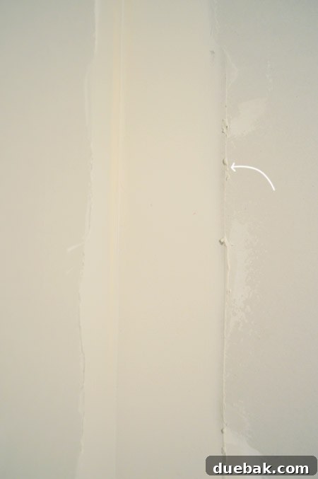 arrow pointing to ridge in drywall mud after scraping excess