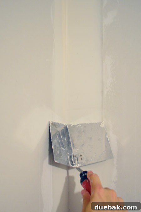 dragging corner trowel down corner of drywalled wall
