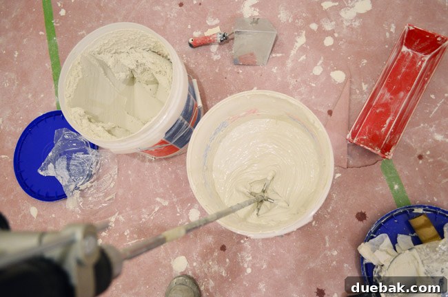 mixing bucket of drywall mud joint compound with drill mixing paddle