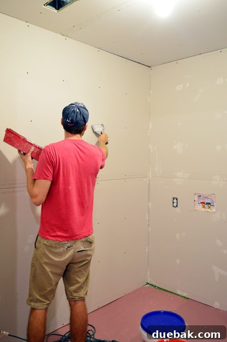 John applying mud over drywall screw head marks