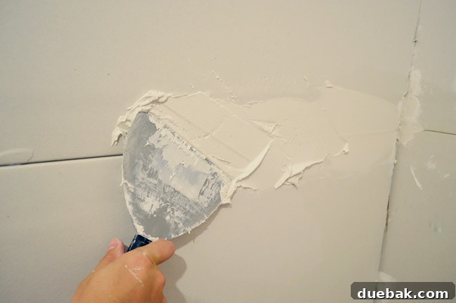 applying thick layer of drywall mud as bed across drywall seams