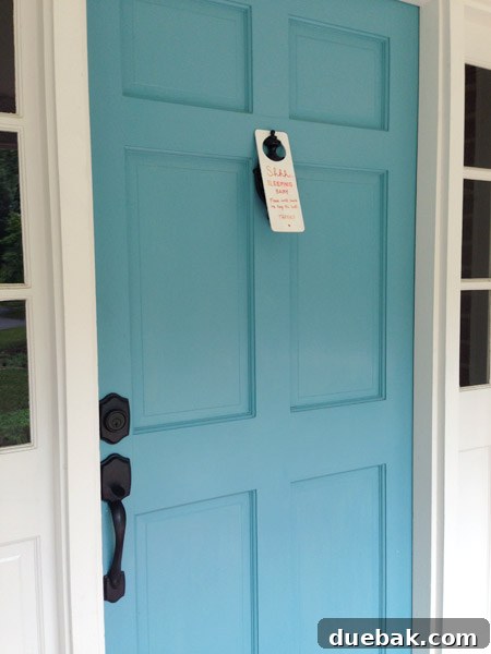 Front door showing a doorknob-less entry with the sign hanging from the knocker