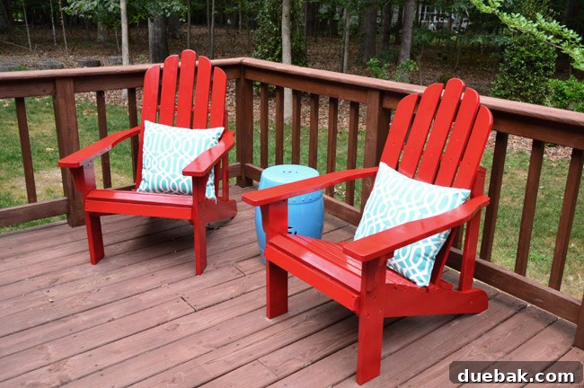 Newly repainted vibrant red Adirondack chairs with outdoor pillows