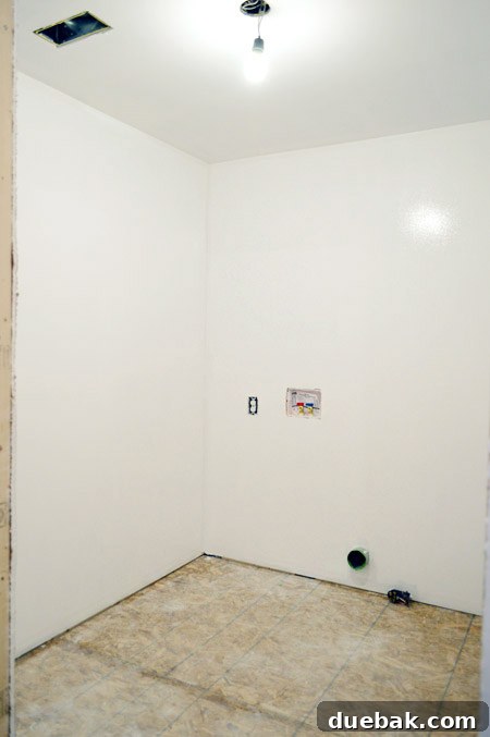 Newly primed small laundry room ready for paint, showcasing clean walls and a compact layout.
