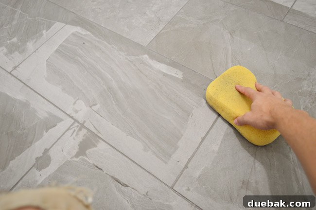 Wiping excess grout with a damp sponge