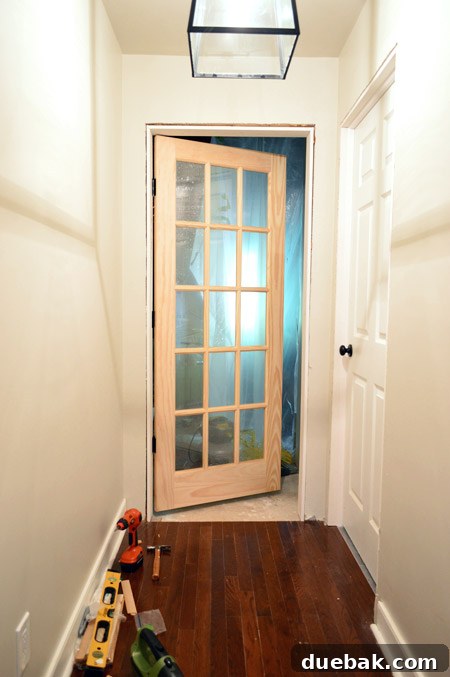 15 Pane Glass Unfinished Wood Door Hung At Entrance To Bonus Room In DIY Door Jamb