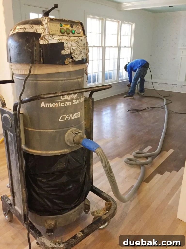 Revitalizing Hardwood Floors The Beginner's Handbook 3 Man diligently sanding hardwood floors using an industrial drum sander for professional results