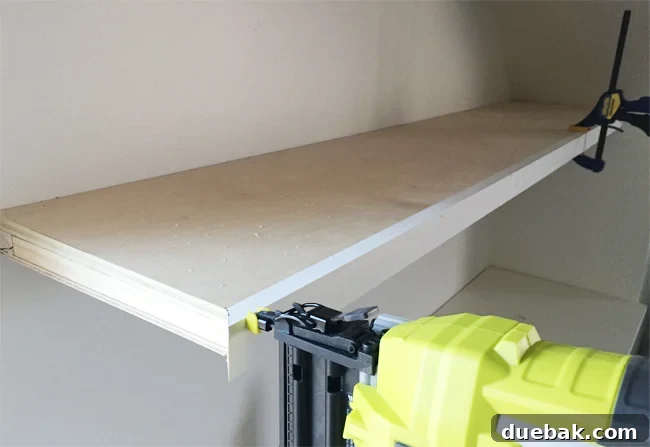 A Ryobi power nailer attaching face pieces of 1x2 pine wood board to thin white floating shelves in bonus room, creating a seamless look