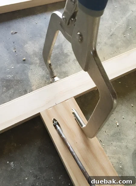 A Kreg jig clamp being used to secure two pieces of wood together at a right angle using a pocket hole screw for robust assembly