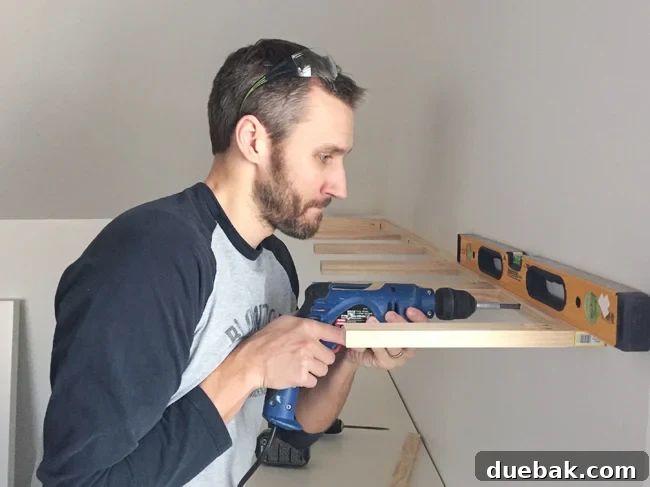 Attaching brace piece for white floating shelves using a power drill driver and level for precision
