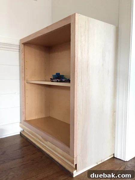 Tailored Book Nooks DIY Built Ins 11 An unfinished end panel securely attached to a base cabinet, beginning to cover the structural blocking for the built-in bookshelf
