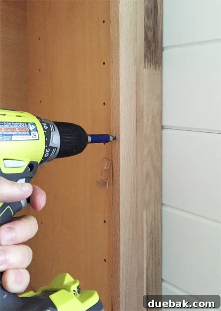 Tailored Book Nooks DIY Built Ins 12 A filler piece being screwed into place next to a base cabinet, demonstrating how to eliminate gaps in built-in shelving