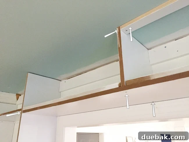 Tailored Book Nooks DIY Built Ins 19 Detailed view of the top shelf installation across a doorway, showing screw points into ceiling blocking and door casing for added support