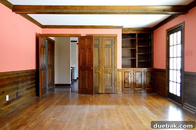 Tailored Book Nooks DIY Built Ins 3 Before photo showing an existing bookshelf in a wood-paneled living room, soon to be transformed