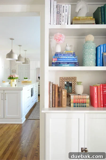 Tailored Book Nooks DIY Built Ins 23 White built-in bookshelves leading into a bright kitchen, styled with books and decor, enhancing the open concept living space