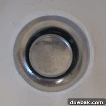 The Secret to Flawless Caulk Lines 7 Close-up of a revitalized bathtub drain with a fresh, clean ring of caulk, demonstrating a significant improvement