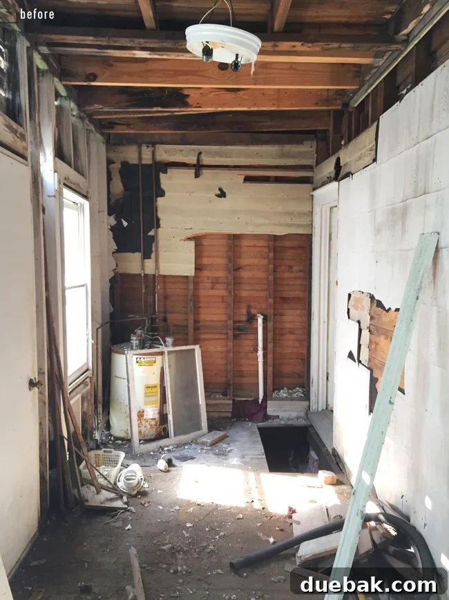 From Studs Up: The Beach House Revival 12 Interior view of the downstairs porch area after demolition, showing exposed framing and damage.