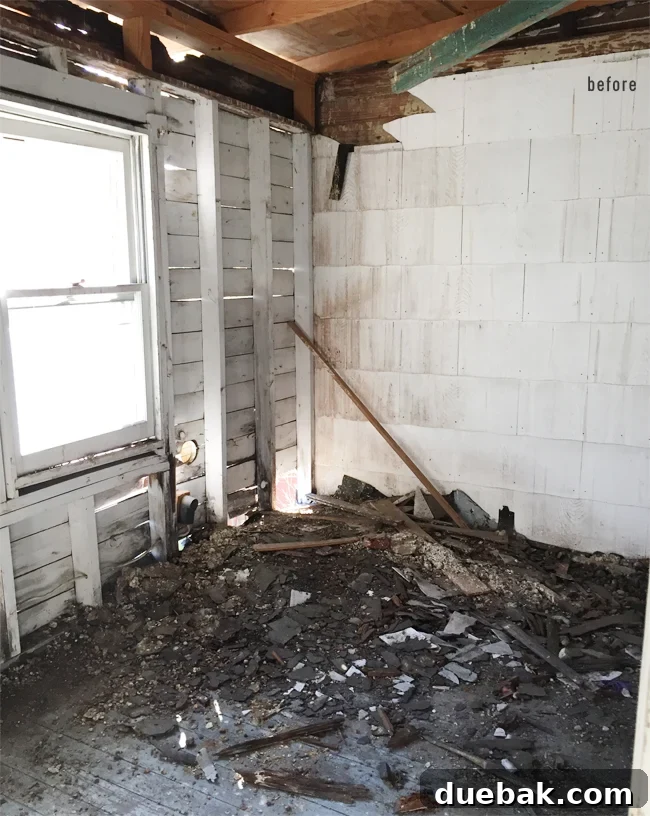 From Studs Up: The Beach House Revival 13 Interior view of the upstairs porch area after demolition, showing extensive damage to the ceiling and framing.