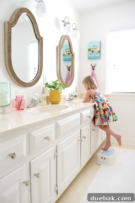 Hall bathroom showcasing two brass mirrors paired with polished nickel hardware and lighting.