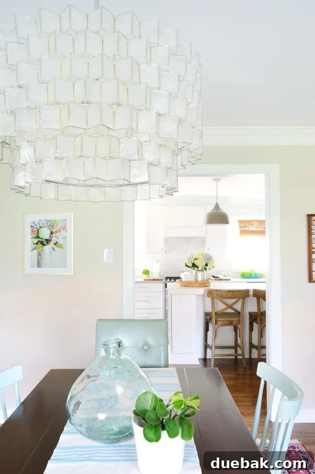 A stylish dining area featuring a modern chandelier, complementing kitchen pendants, and various seating options, illustrating cohesive lighting choices