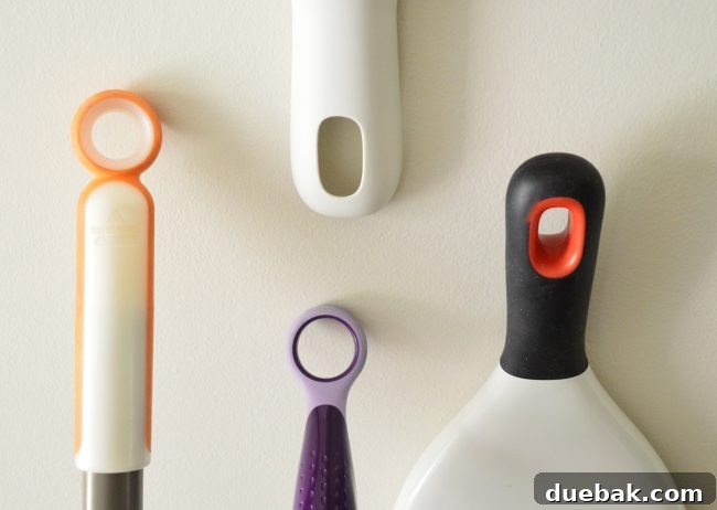 Unlock 1000 Dollars in Savings With This Home Habit 3 Three cleaning tools hanging neatly in a closet, showing their handles and hanging holes: a Swiffer Wet Jet, a Bissell Pet Hair Broom, and an OXO Good Dustpan & Brush.