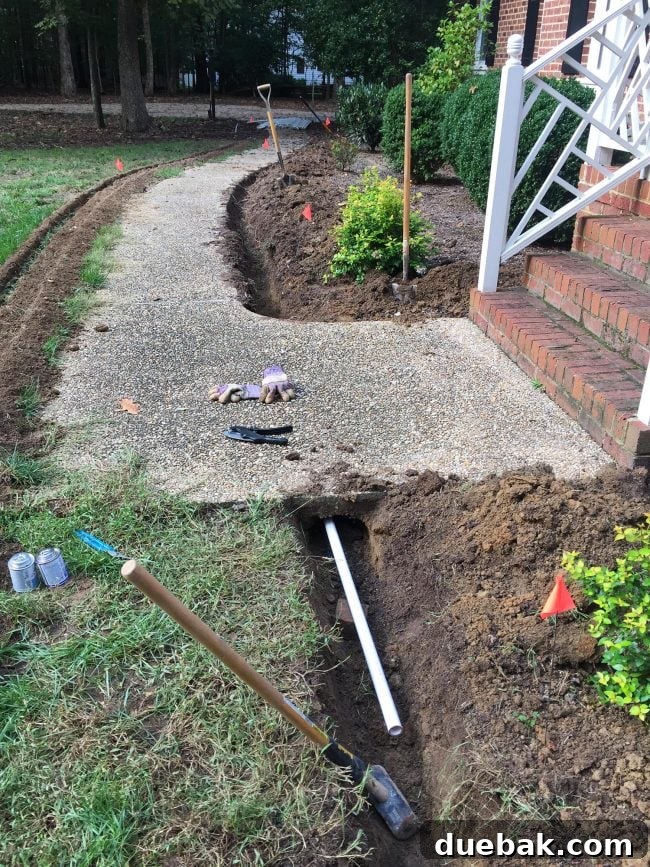 Installation of irrigation system pipe being manually pushed under a concrete sidewalk