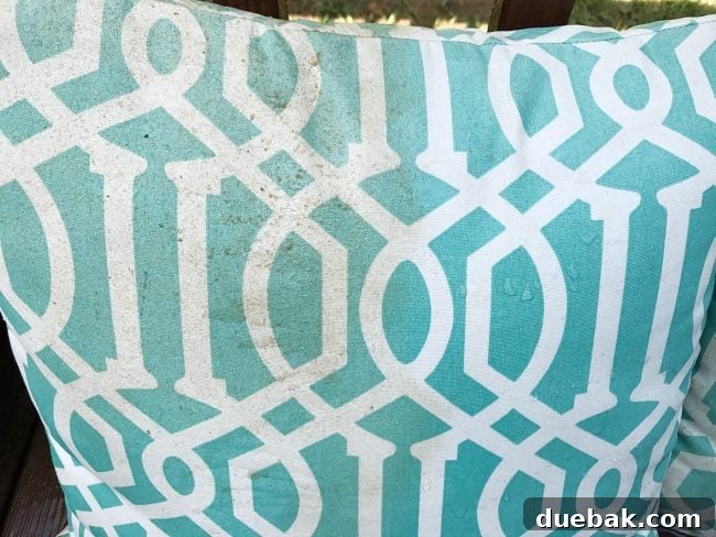 An outdoor cushion, half-cleaned with a pressure washer, clearly showing the contrast between the dirty and clean sections.