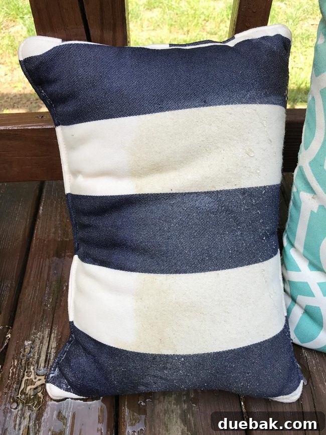 Another outdoor pillow partially cleaned by a pressure washer, revealing a distinct, clean stripe on the fabric.