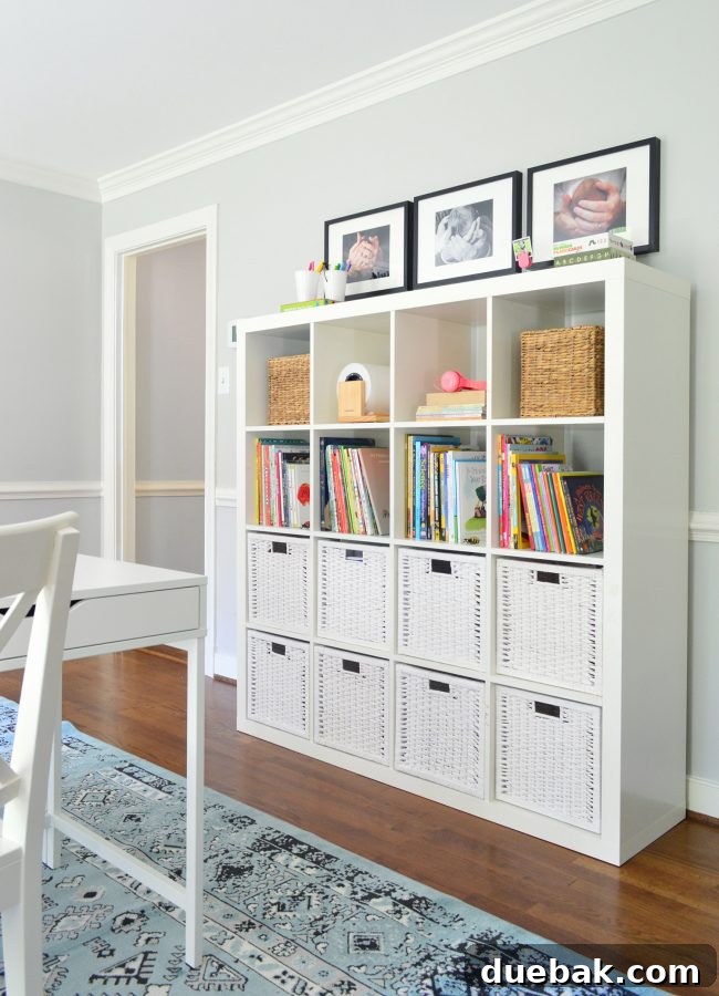 Gridded bookcase with white baskets and framed baby photos in kids' study