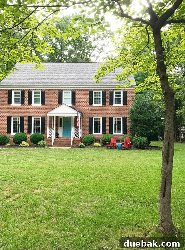 Patriotic Curb Appeal 3 A picturesque patriotic front porch on a classic colonial home, adorned with an American flag and inviting outdoor seating, ready for summer relaxation.
