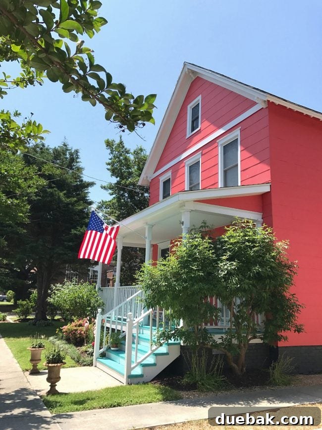 Patriotic Curb Appeal 6 A vibrant patriotic front porch on a bright pink house, featuring contrasting blue porch stairs, creating a playful and eye-catching exterior design.