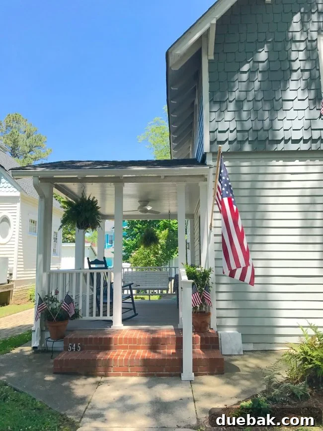 Patriotic Curb Appeal 7 A welcoming patriotic front porch on a charming shingled beach house, adorned with flags and outdoor decor, perfect for coastal living.