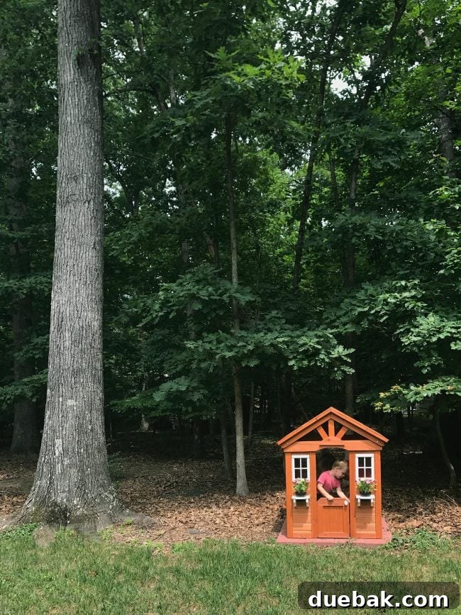 Charming cedar wooden playhouse nestled beside a large tree in the backyard
