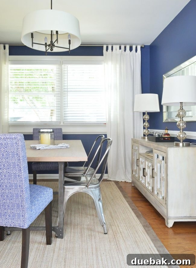 Modern dining room with deep blue walls, white curtains, and wood furniture