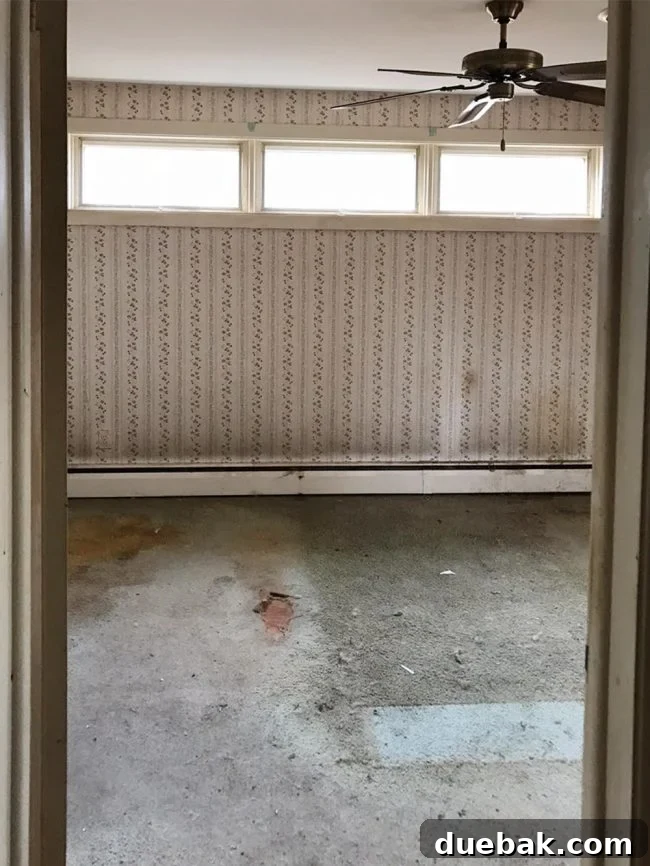 Before photo of a master bedroom with dated wallpaper