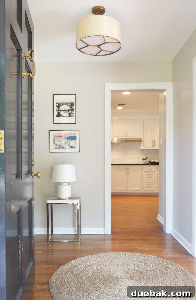 Transformed foyer with dark door, sculptural light, and elegant decor