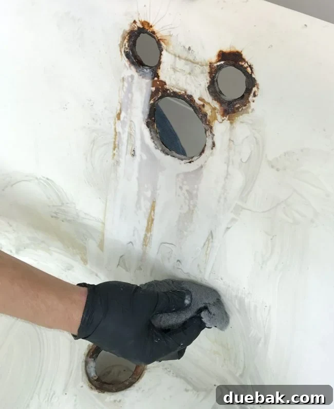 Wiping away stains in a clawfoot tub with a steel wool sponge for deep cleaning