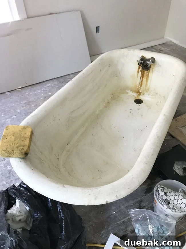 Dirty inside of an old clawfoot tub being cleaned with a sponge