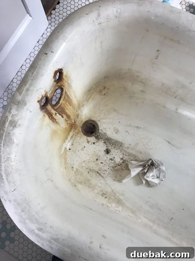 Close-up of rust stains visible around the faucet holes in an old clawfoot tub