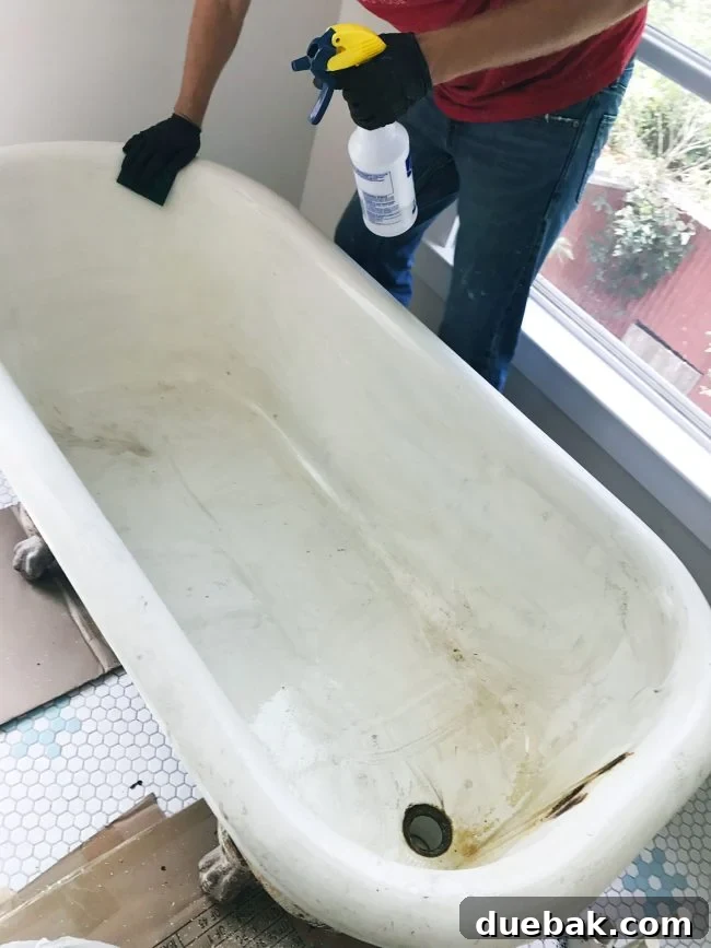Cleaning the inside of a clawfoot tub with a sponge and vinegar solution